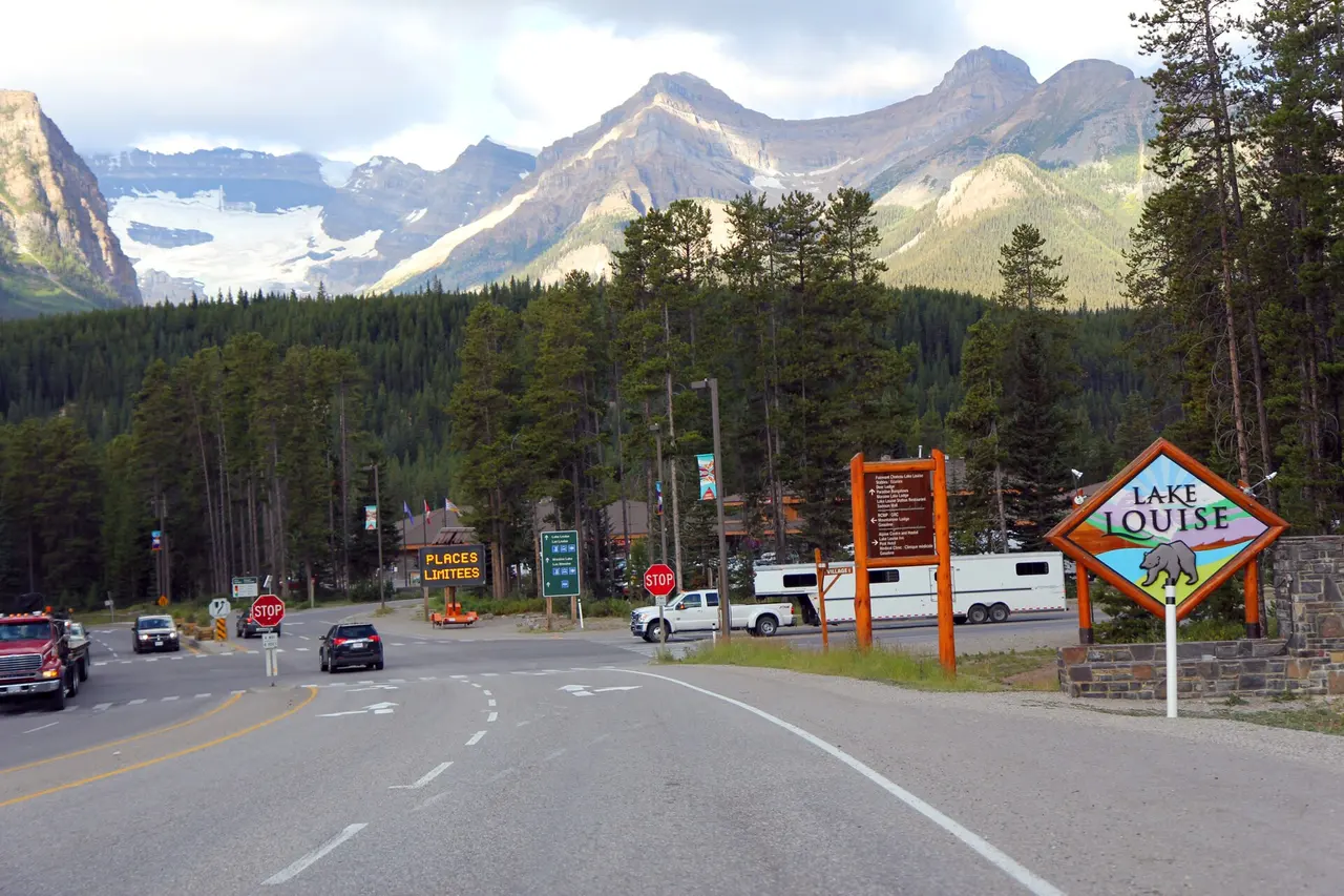 The Parks Canada entrance sign for Lake Louise beside the highway with forested mountains behind