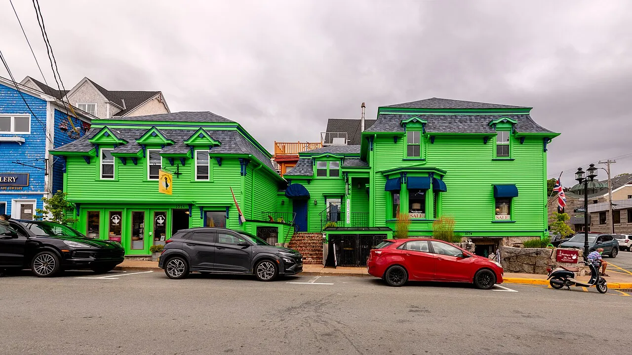 Brightly painted green and blue wooden heritage buildings on a sloping street in Old Town Lunenburg