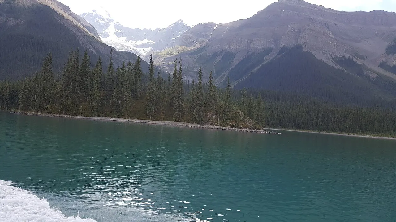 A glacier-carved valley and turquoise water seen from the deck of a Maligne Lake cruise boat