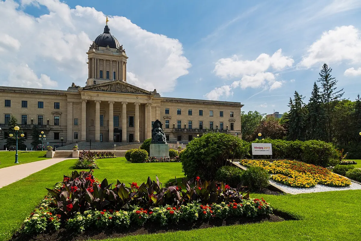 The neoclassical Manitoba Legislative Building behind formal green gardens in Winnipeg