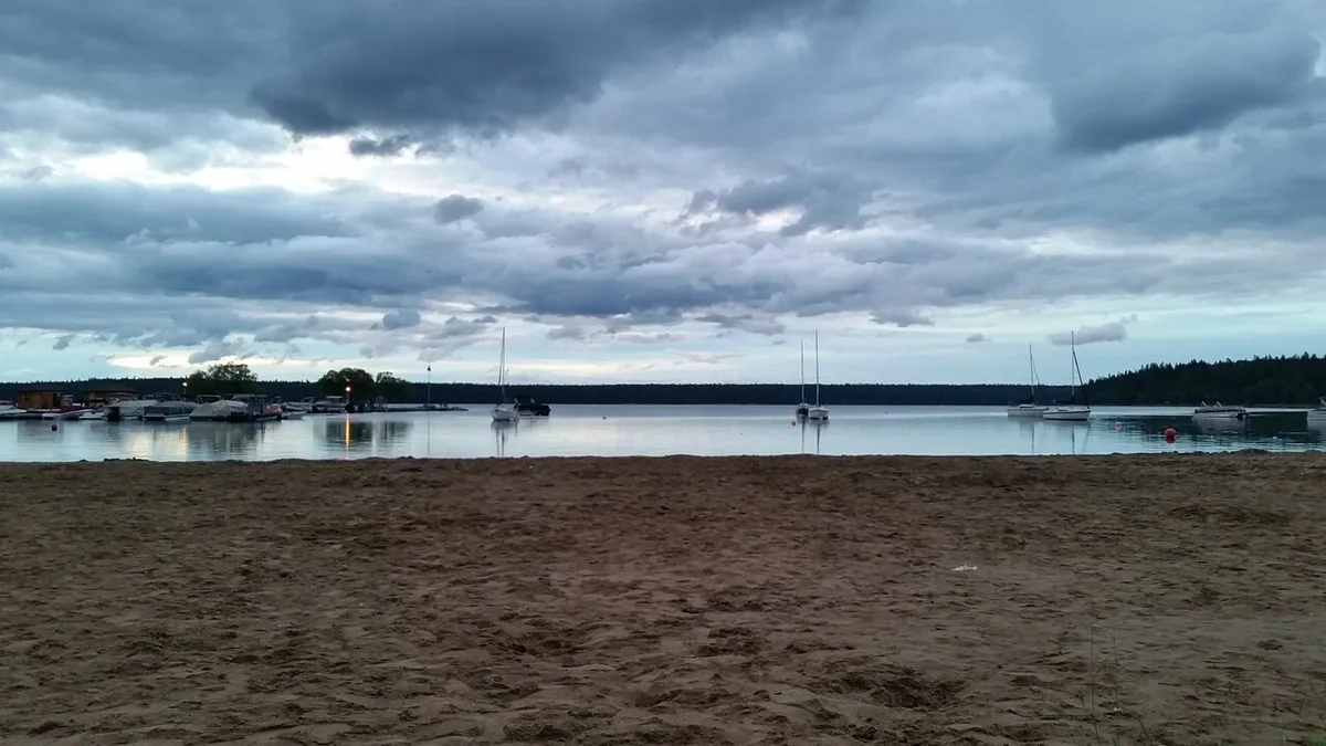 The sandy main beach at Wasagaming on Clear Lake, ringed by forest in Riding Mountain National Park