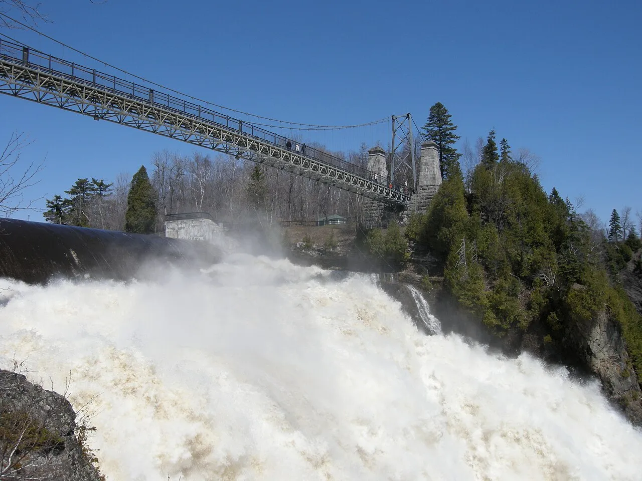 Visitors crossing the suspension bridge directly above the crest of Montmorency Falls