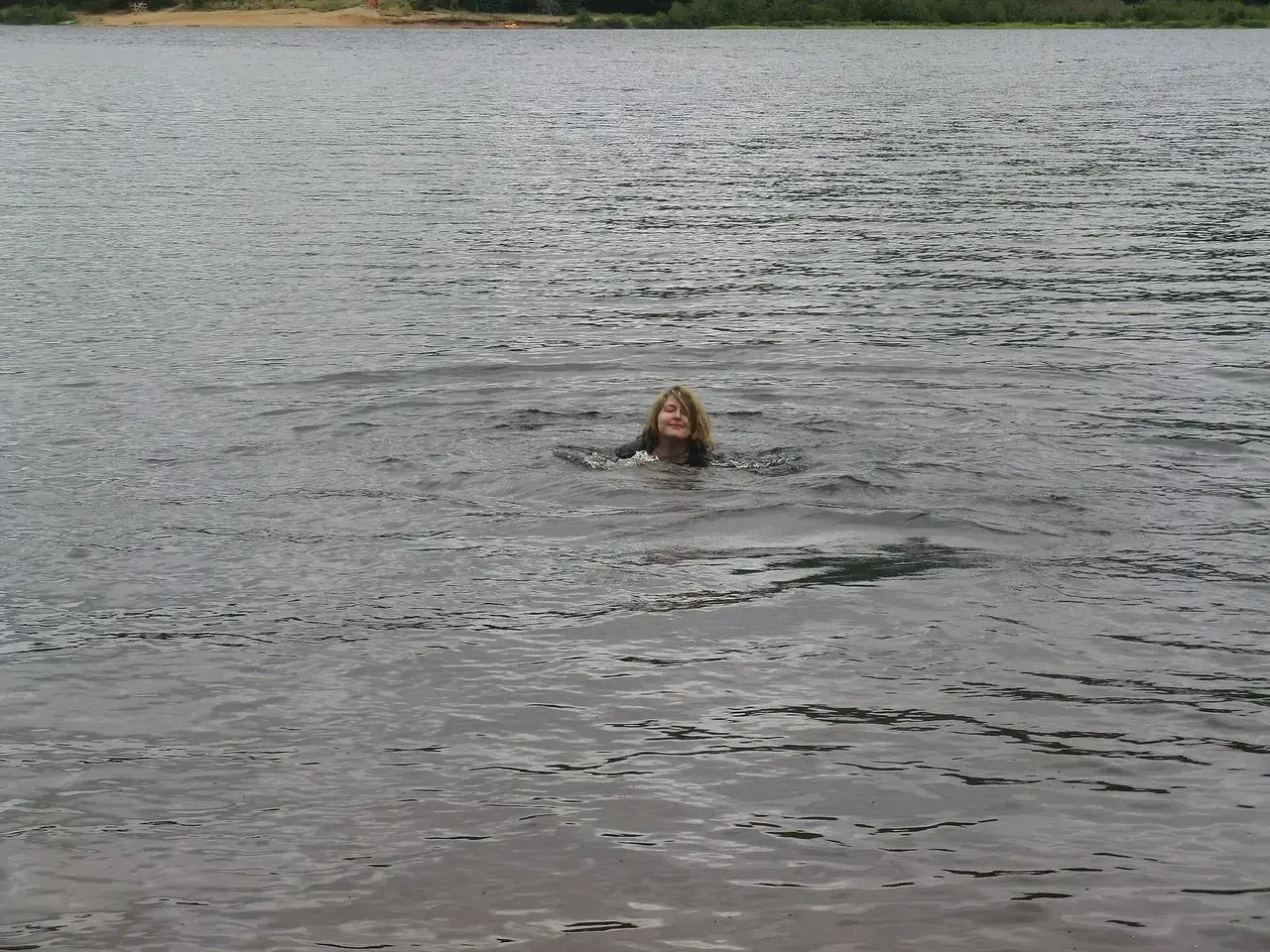 A swimmer in the open water of Lac Monroe, the far shore wooded behind