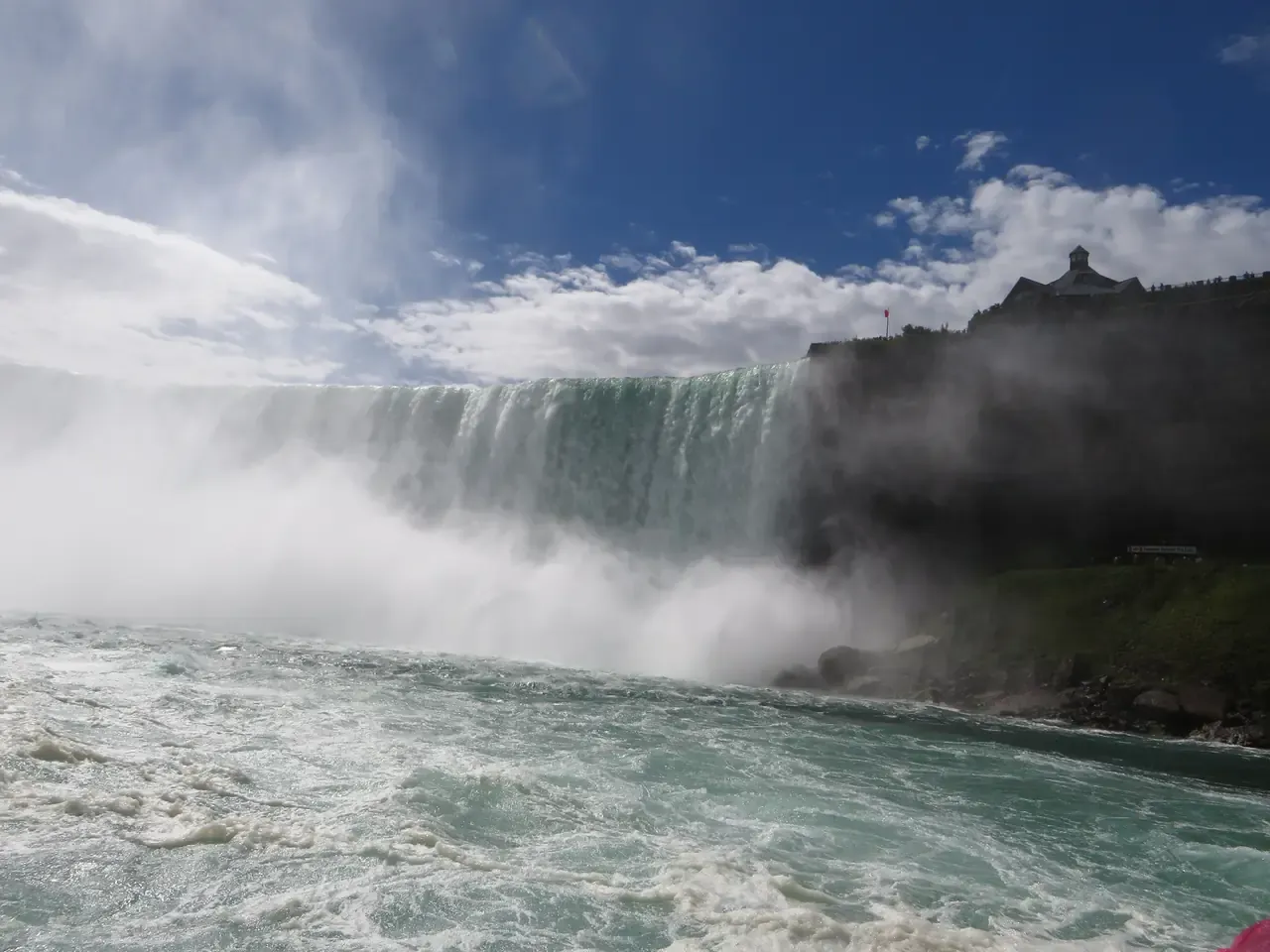 Looking up at the curved Horseshoe Falls from a Niagara City Cruises boat deck