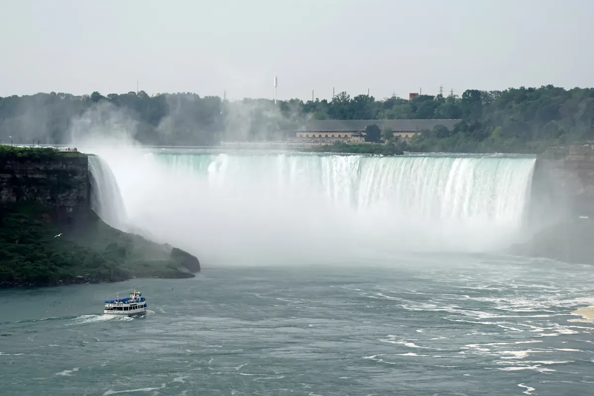 A tour boat crowded with passengers in ponchos approaching the base of the Canadian falls