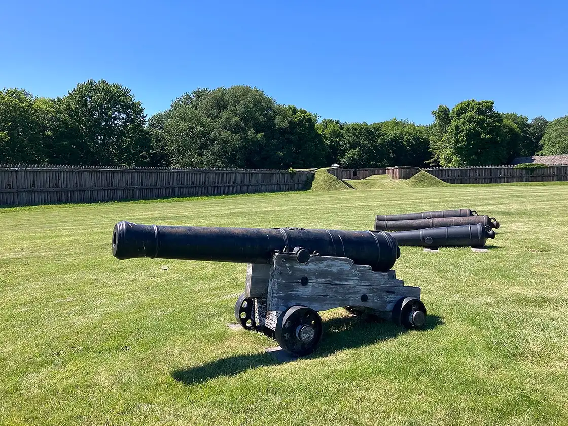 A row of period cannons on the grass parade ground inside Fort George National Historic Site