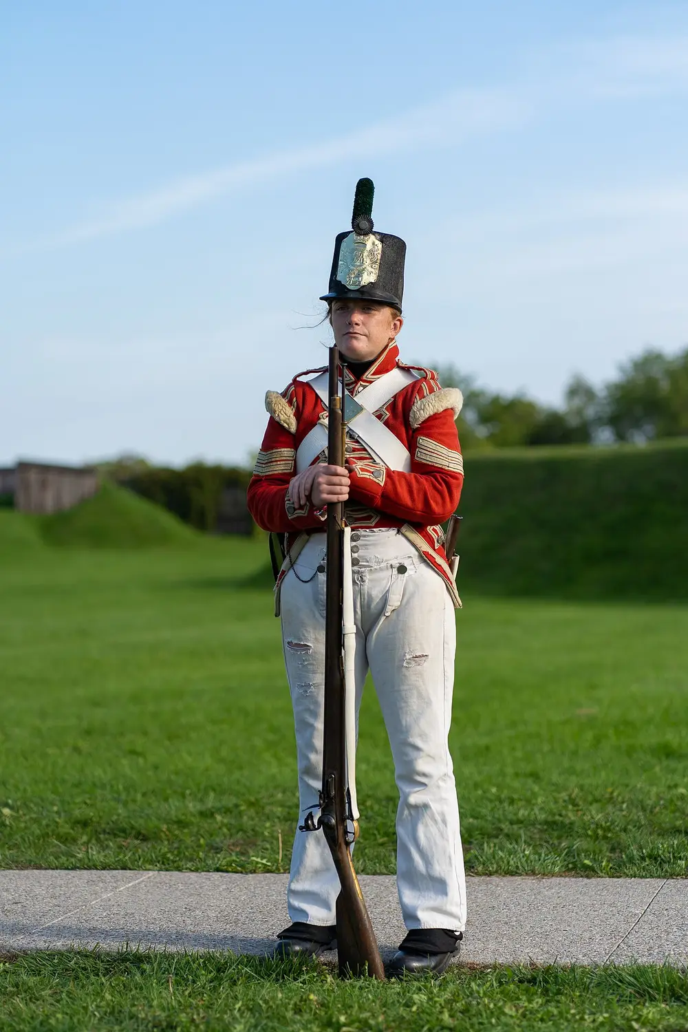 A costumed reenactor in an 1812-period British Army uniform standing inside Fort George