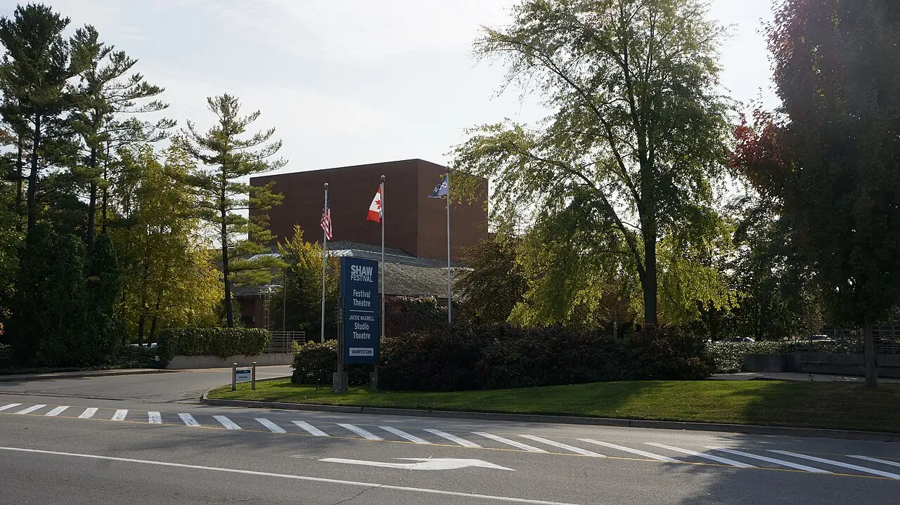 The Shaw Festival Theatre building behind trees and flagpoles in Niagara-on-the-Lake