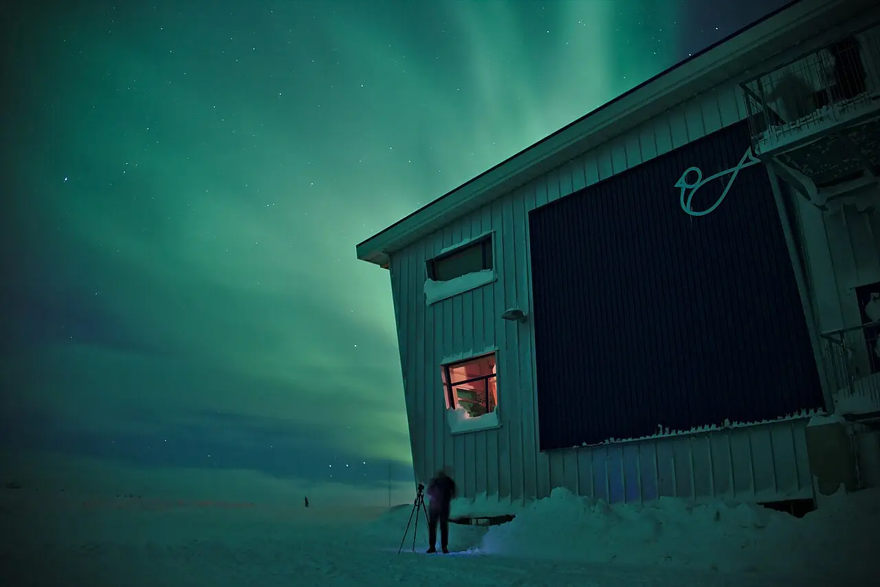 The silhouette of the Churchill Northern Studies Centre under a faint aurora