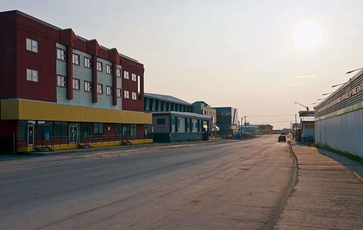 Low evening sunlight over the main street and buildings of Inuvik under a bright northern sky