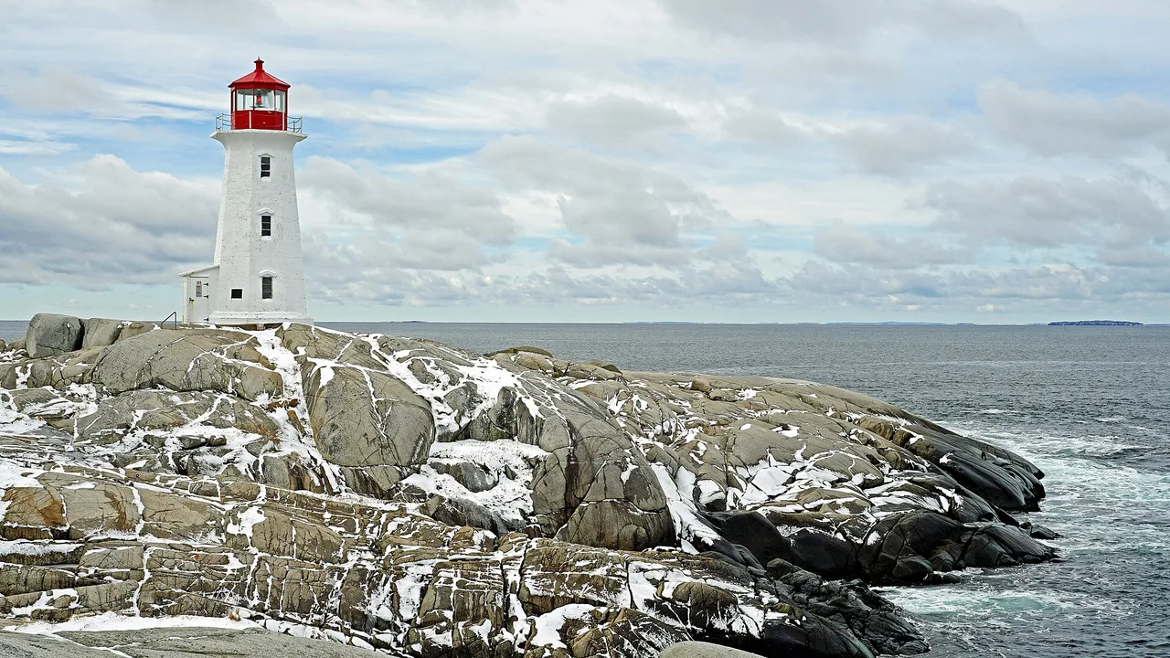 Peggy's Point Lighthouse, a white tower with a red top, on wave-washed granite above the open Atlantic
