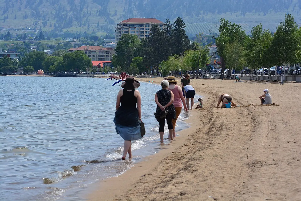 Swimmers and sunbathers on Okanagan Beach at Penticton with hills across the water