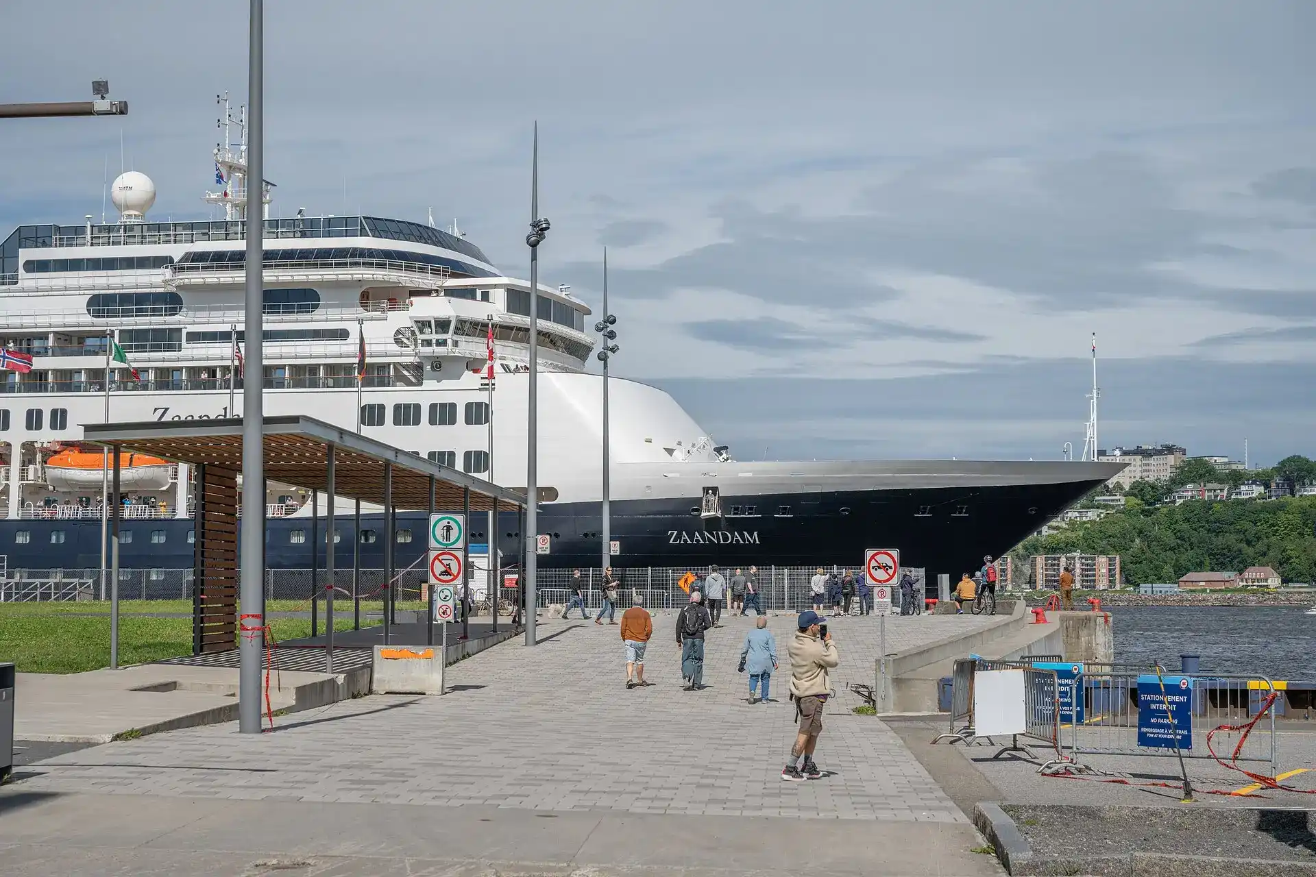 Passengers from a docked cruise ship walking along the quay below Old Quebec toward the historic district