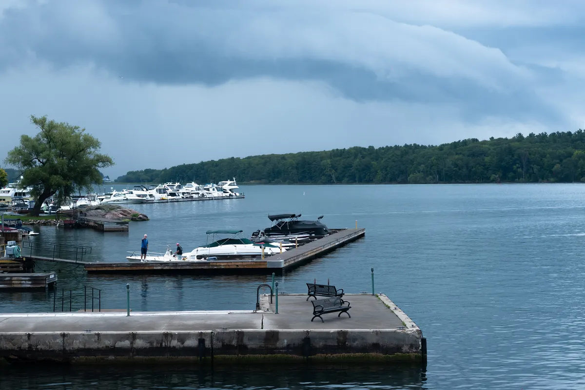 A wooden pier reaching into the calm St. Lawrence River among the wooded Thousand Islands