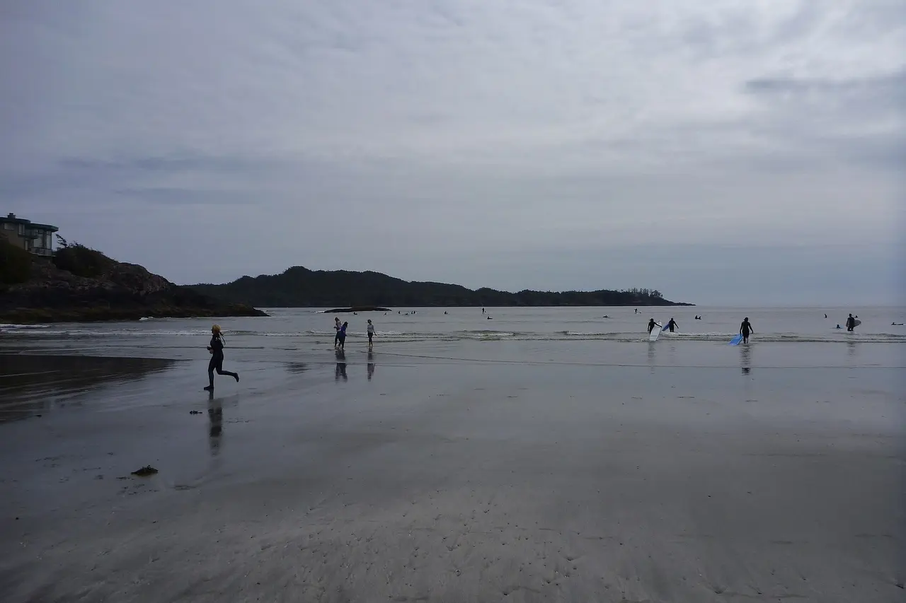 Surfers carrying boards toward the water at Chesterman Beach near Tofino