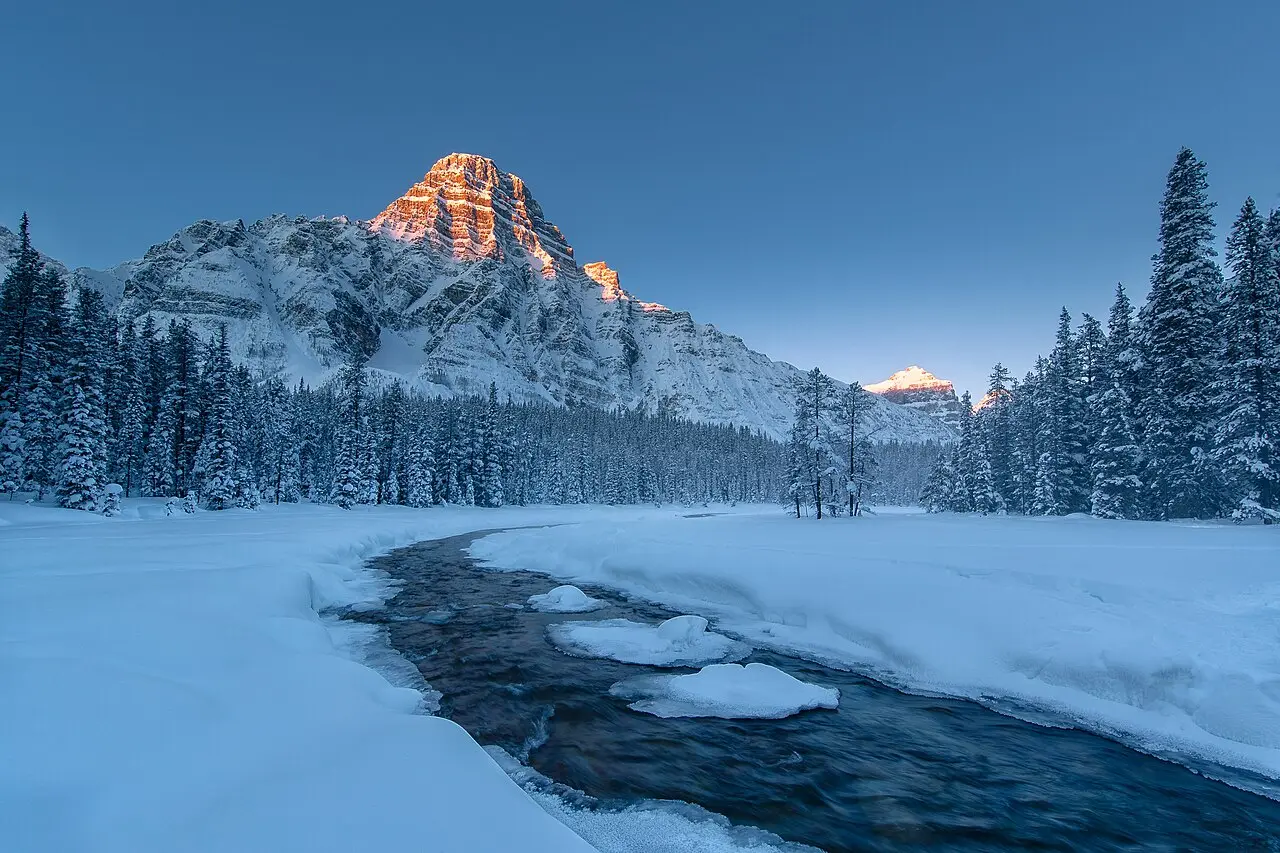 A frozen winter morning landscape in the Canadian Rockies with snow-covered peaks and a still valley