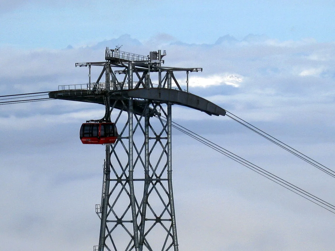 A red Peak 2 Peak gondola cabin hanging from its tower high above a sea of cloud at Whistler Blackcomb