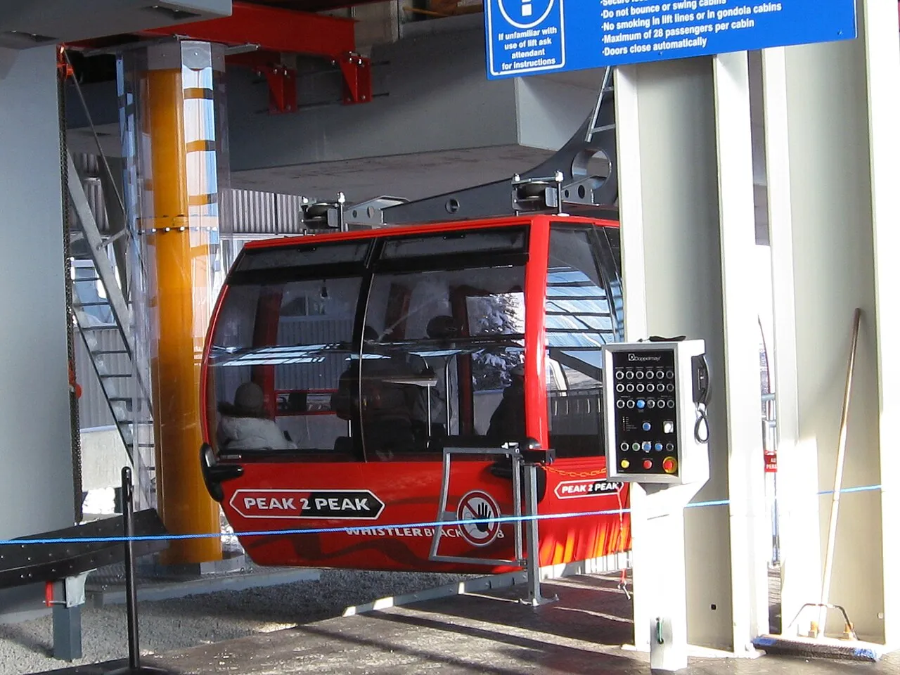 A red Peak 2 Peak gondola cabin departing the Whistler station with a passenger capacity sign visible