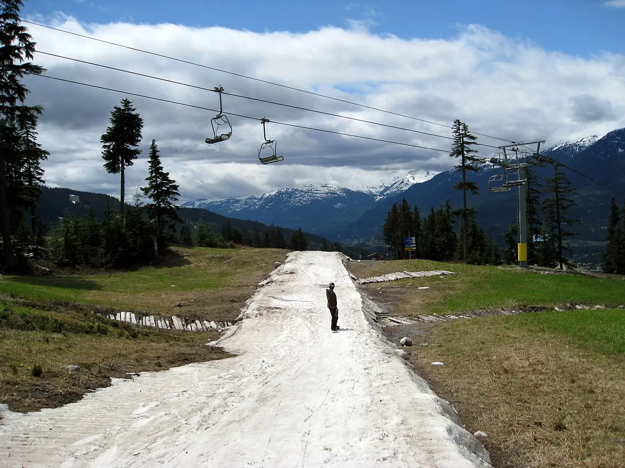 A snowboarder riding alone down an open winter run at Whistler Blackcomb