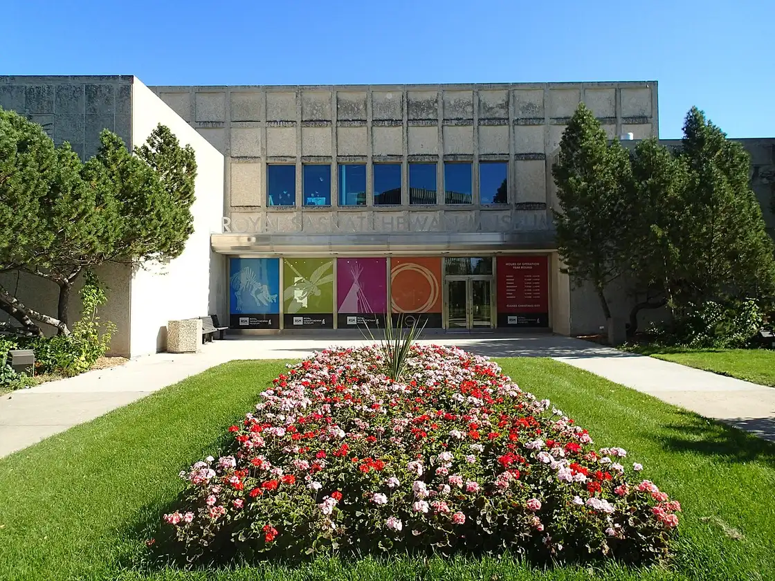 The main entrance of the Royal Saskatchewan Museum in Regina, with banners under the canopy and a flowerbed in front
