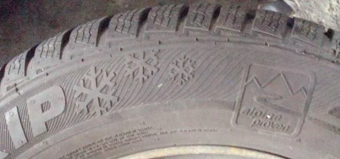 Close-up of the alpine three-peak snowflake symbol moulded into the sidewall of a real tire