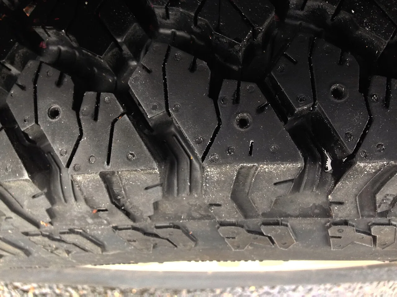 Close-up of a winter tire tread showing the blocks and moulded holes for studs