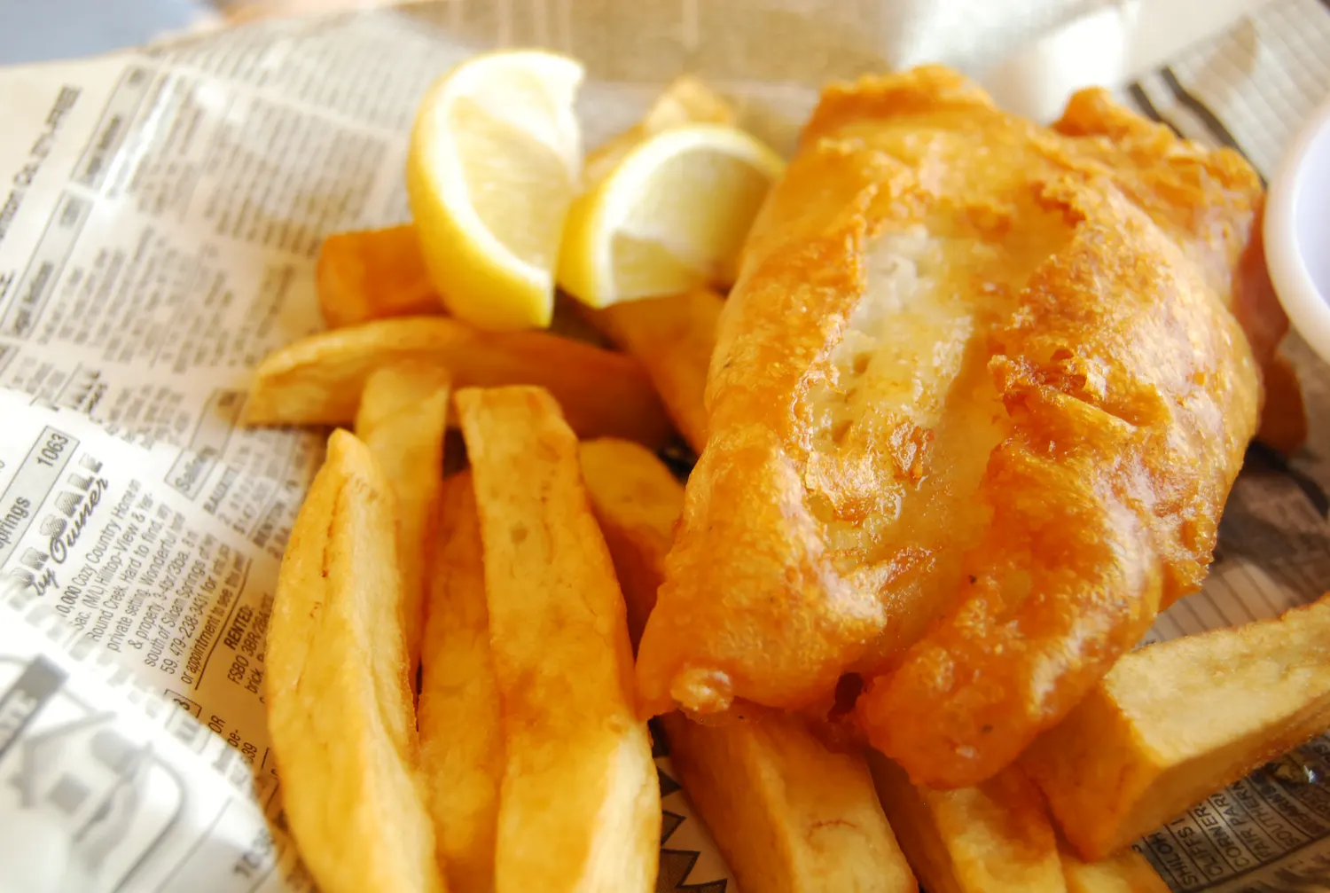 A basket of beer-battered fish and chips with lemon wedges, the style of fish and chips served at Go Fish in Vancouver