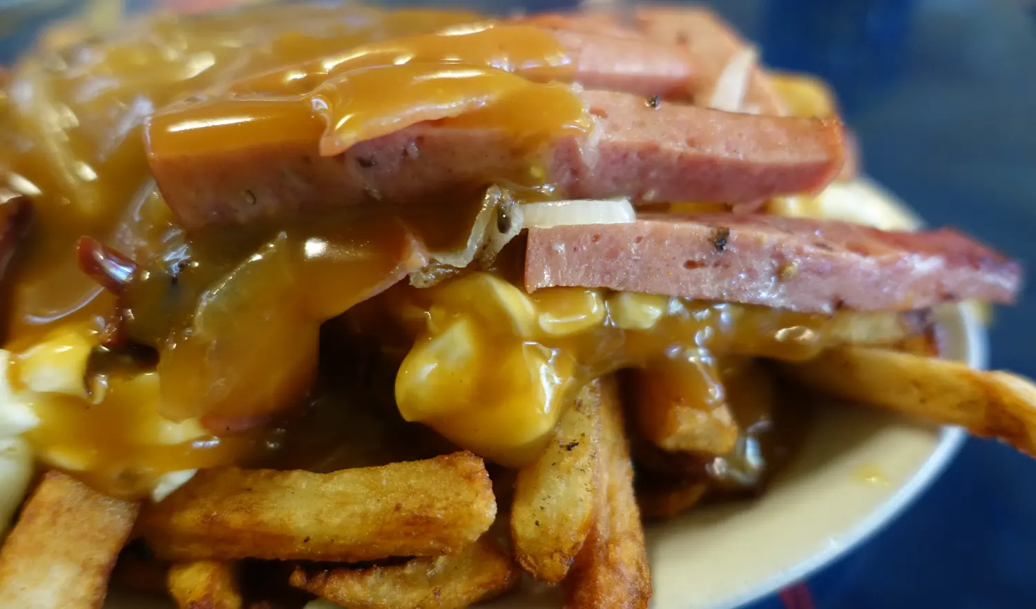 Close-up of a loaded poutine with sliced sausage, gravy and cheese curds at La Banquise in Montreal