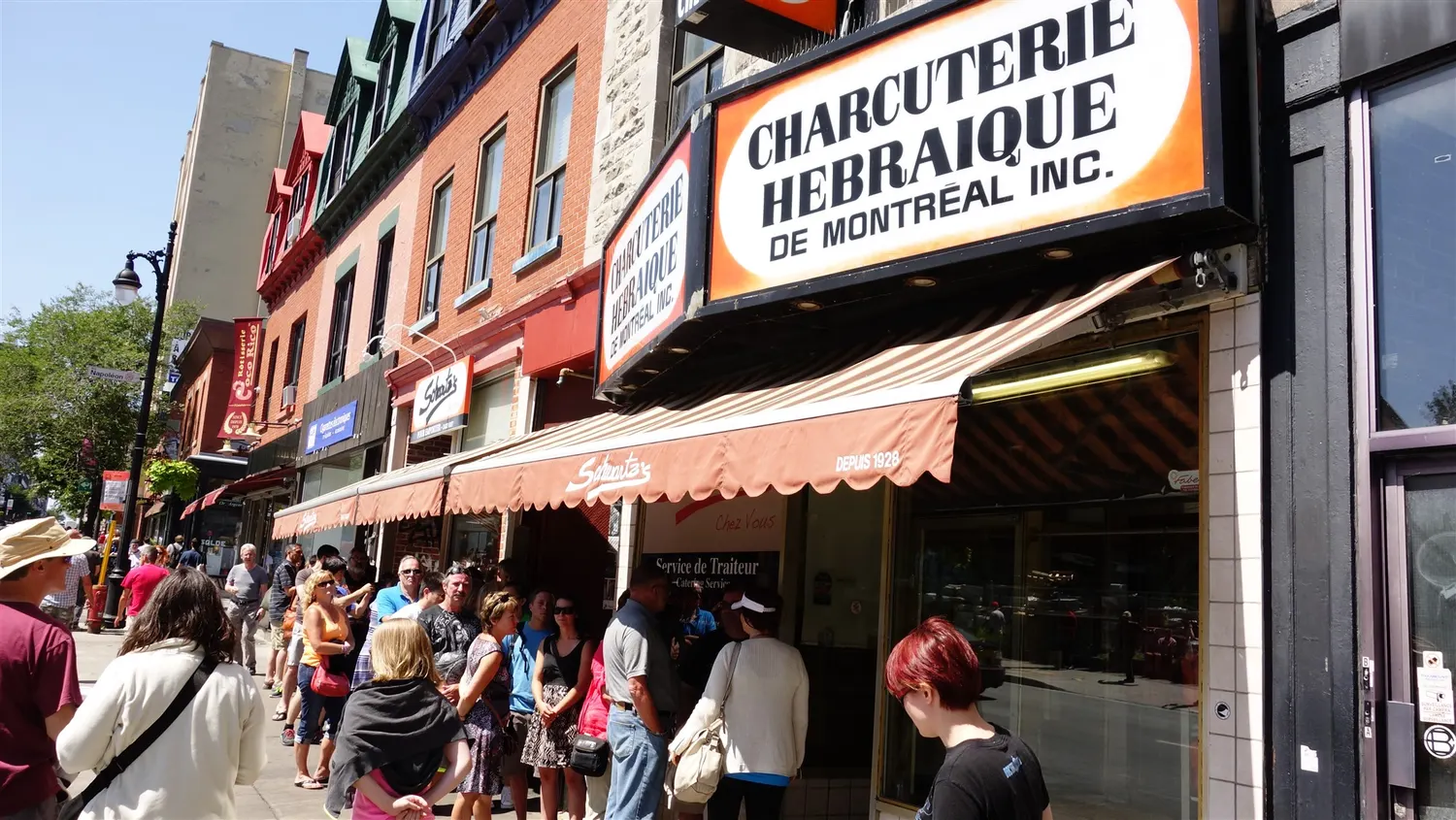 Crowd queuing outside the Charcuterie Hebraique de Montreal sign at Schwartz's Deli on Boulevard Saint-Laurent
