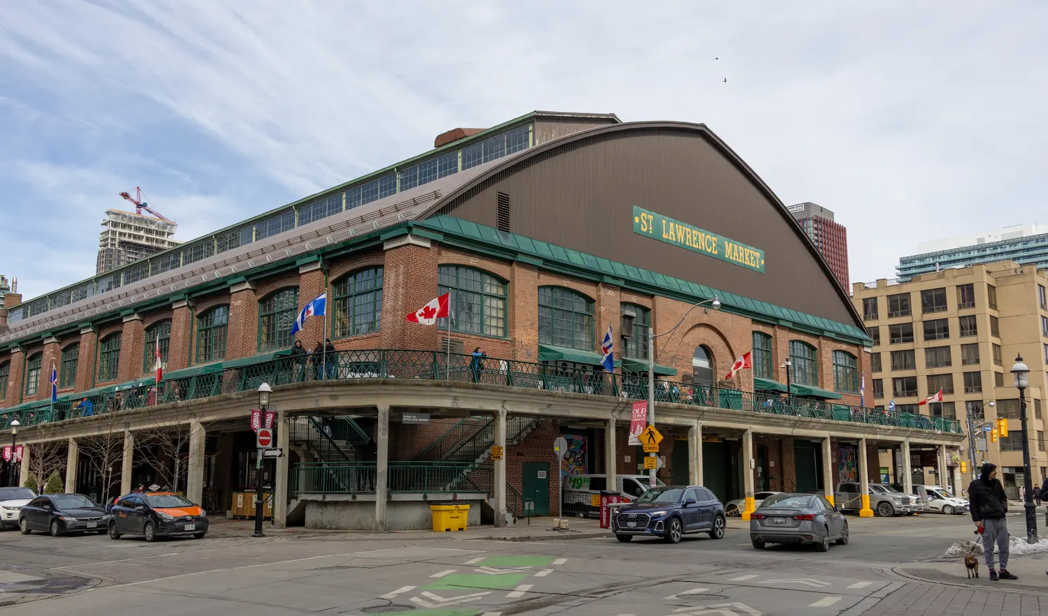 The brick South Market building of St. Lawrence Market in Toronto with its rooftop sign and Canadian flags
