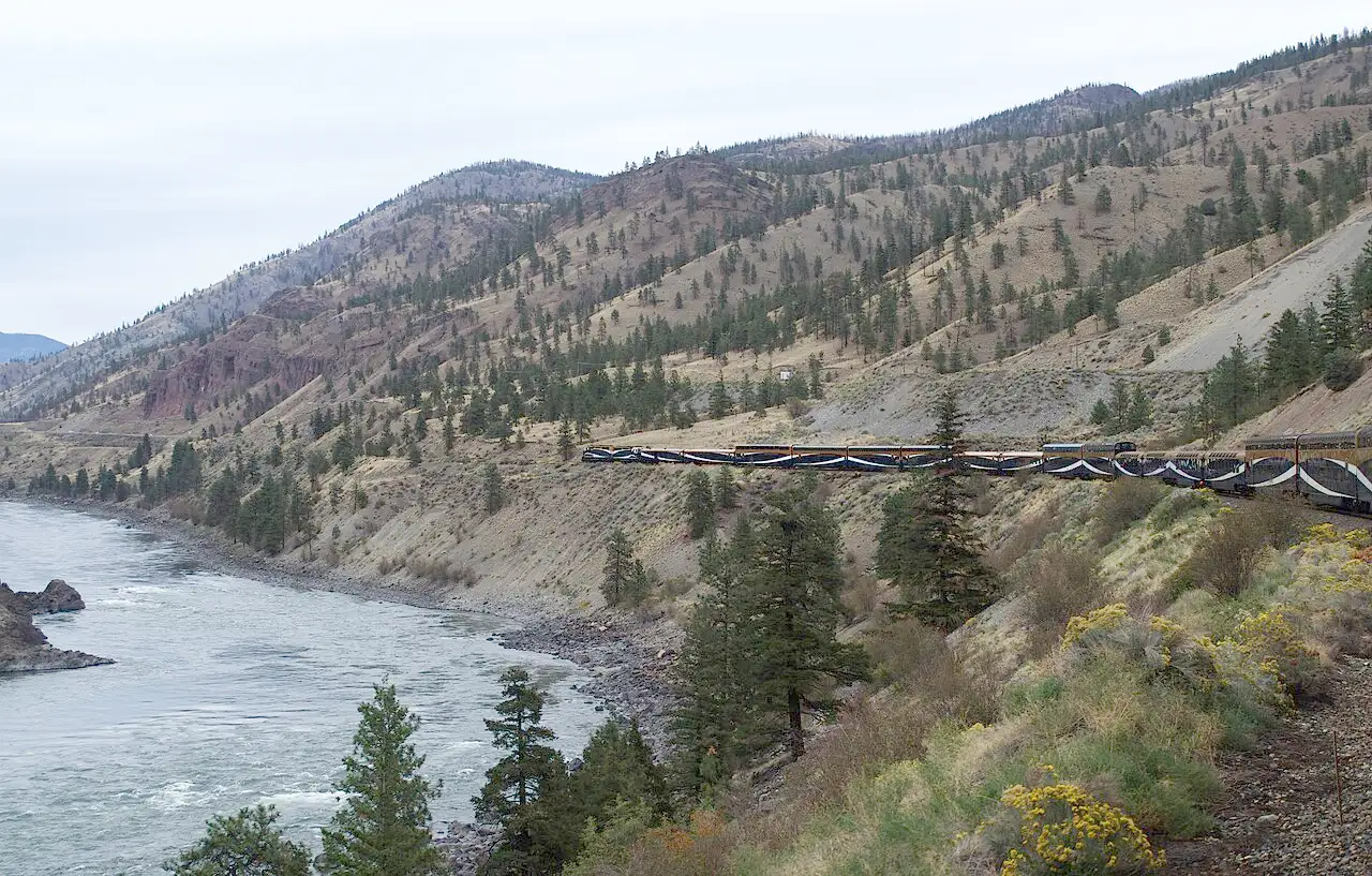 Rocky Mountaineer train running through forested canyon country near Lytton, BC