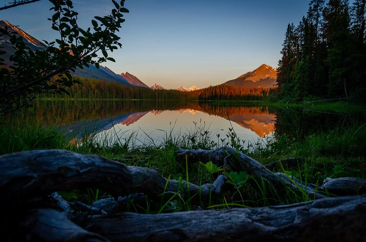 Motorhomes and tents at Honeymoon Lake Campground at sunset with mountains reflected in still water