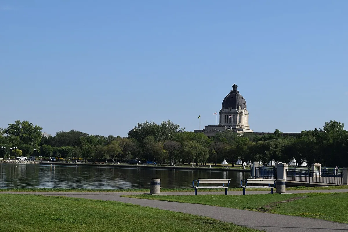 The domed Saskatchewan Legislative Building reflected across the calm water of Wascana Lake in Regina
