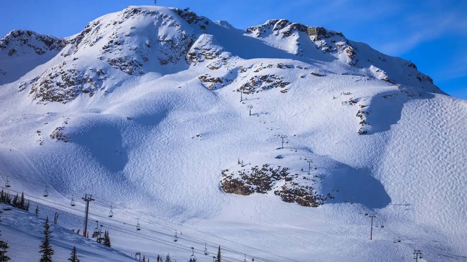 A snow-covered alpine bowl above the treeline at Whistler Blackcomb with chairlifts running up the slope