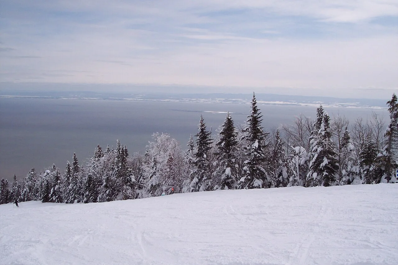 A ski run at Le Massif de Charlevoix dropping toward the wide St Lawrence River below