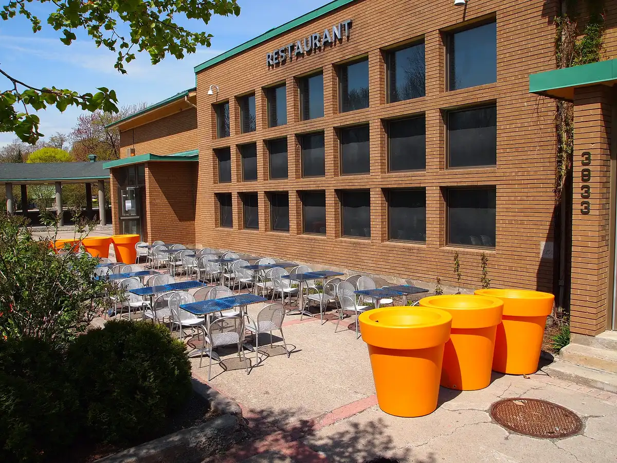 An outdoor restaurant terrace with metal tables and chairs beside a brick building in Montreal