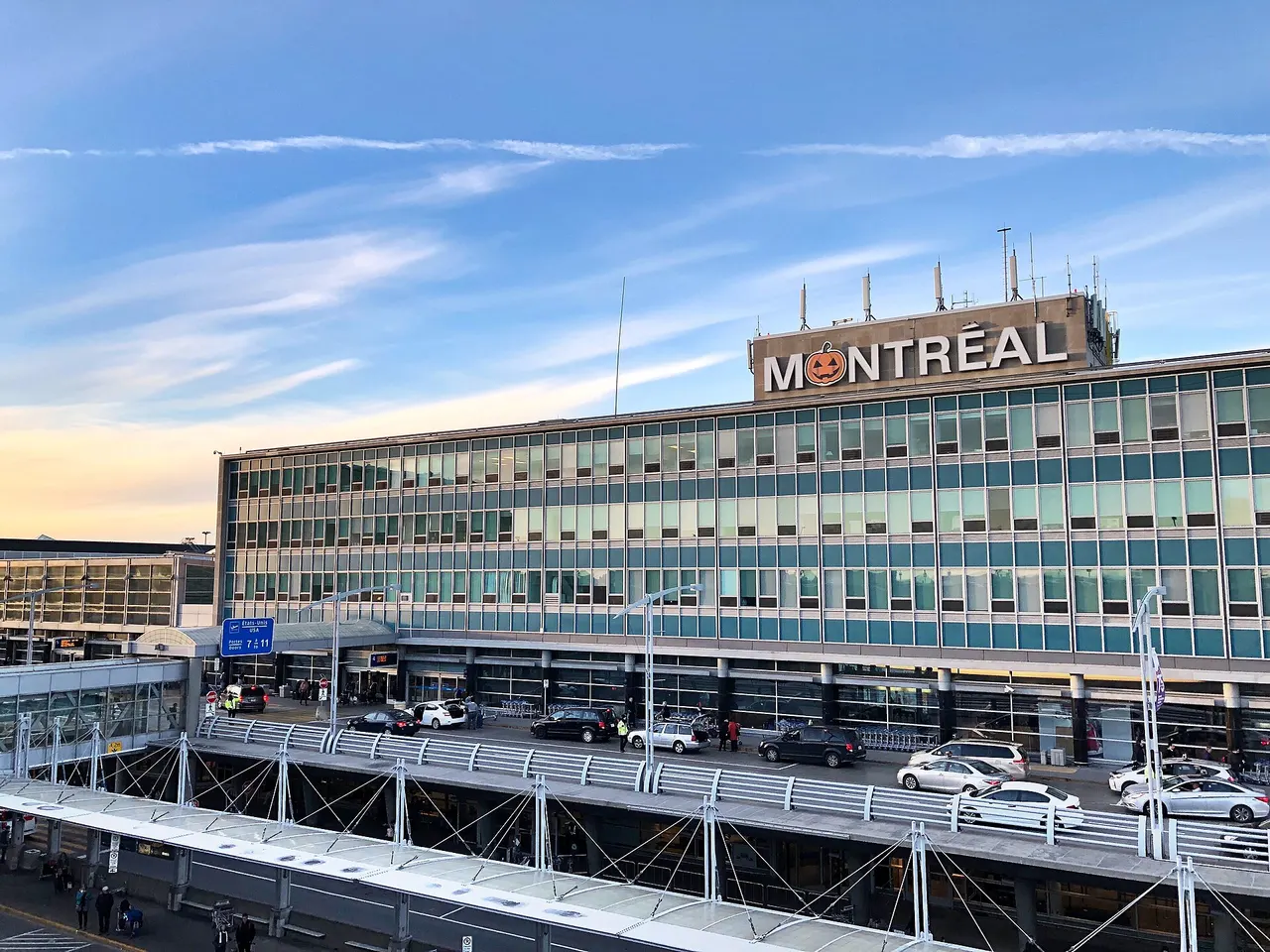 Curved glass façade of Montreal-Trudeau airport terminal under a blue sky
