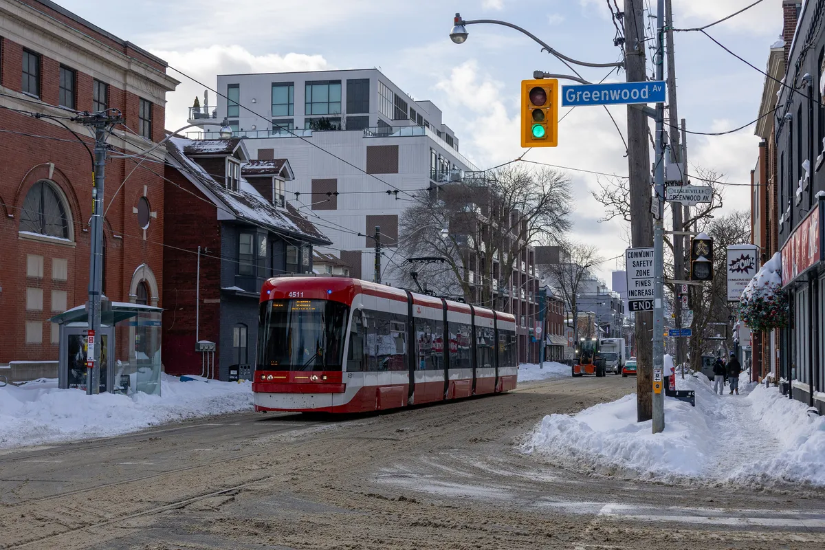 A red-and-white 501 Queen streetcar on Queen Street East in Toronto