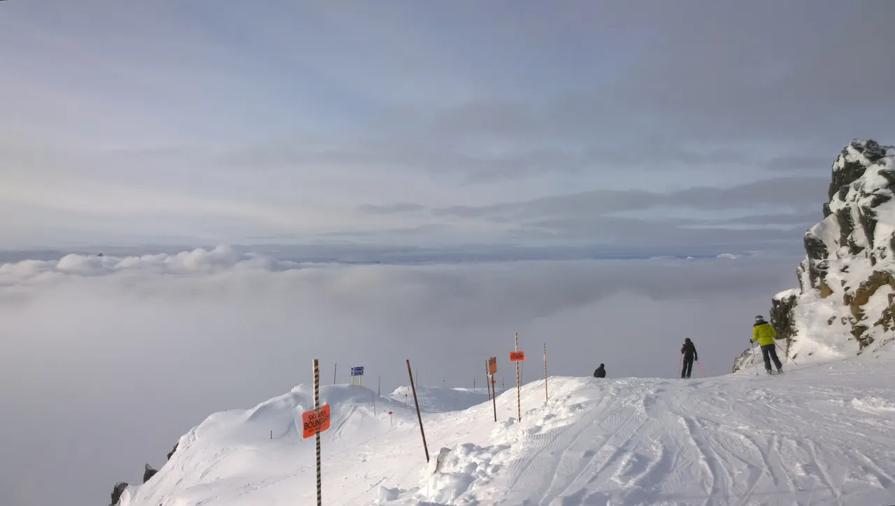 A skier on a high open slope above the clouds at a British Columbia ski resort