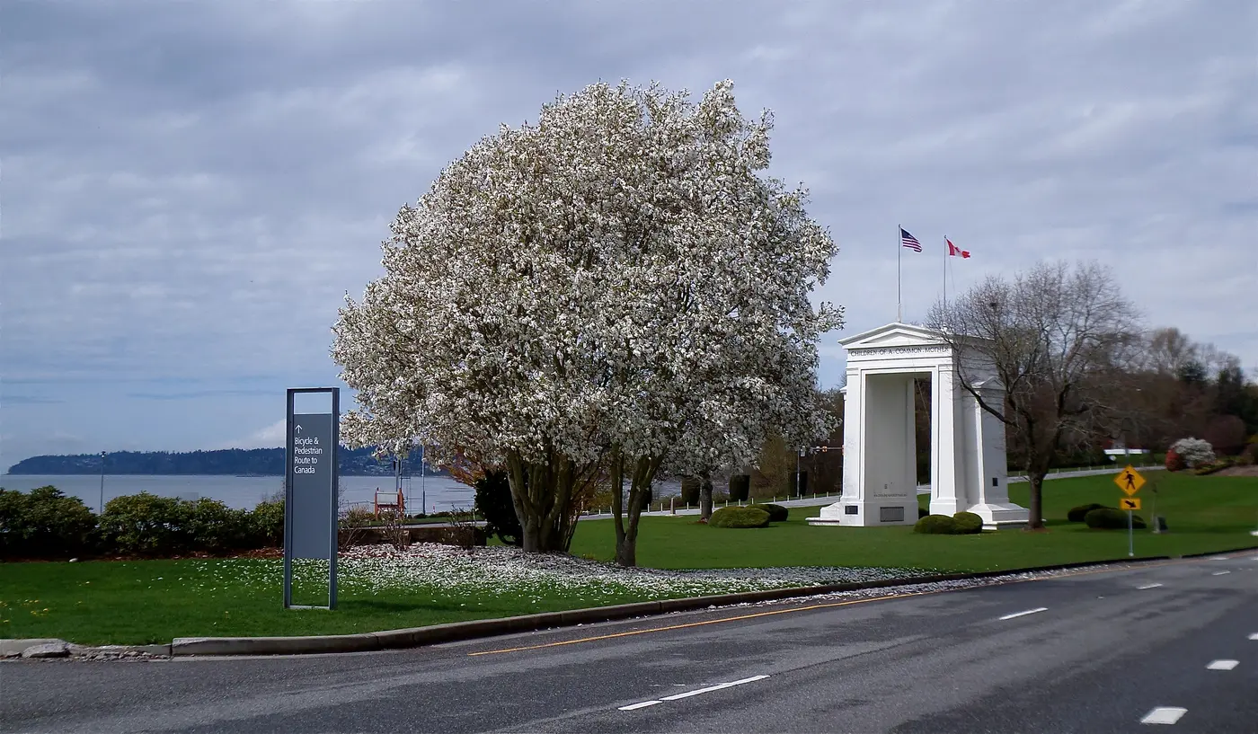 The white Peace Arch monument straddling the USA-Canada border at Blaine, Washington, with flowers and green lawns around it