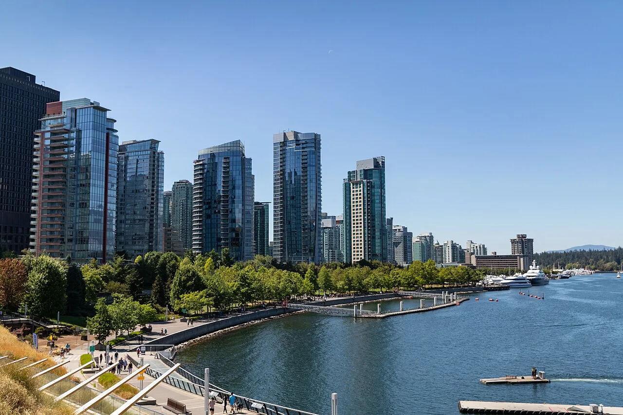 The downtown Vancouver skyline of glass towers rising behind the boats and blue water of the harbour