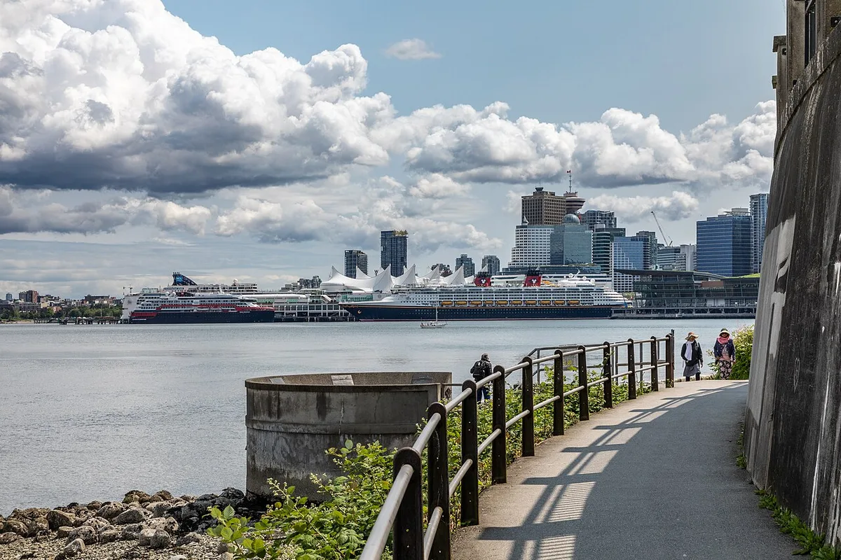 The paved Stanley Park Seawall path curving along the shoreline with the sea on one side and trees on the other