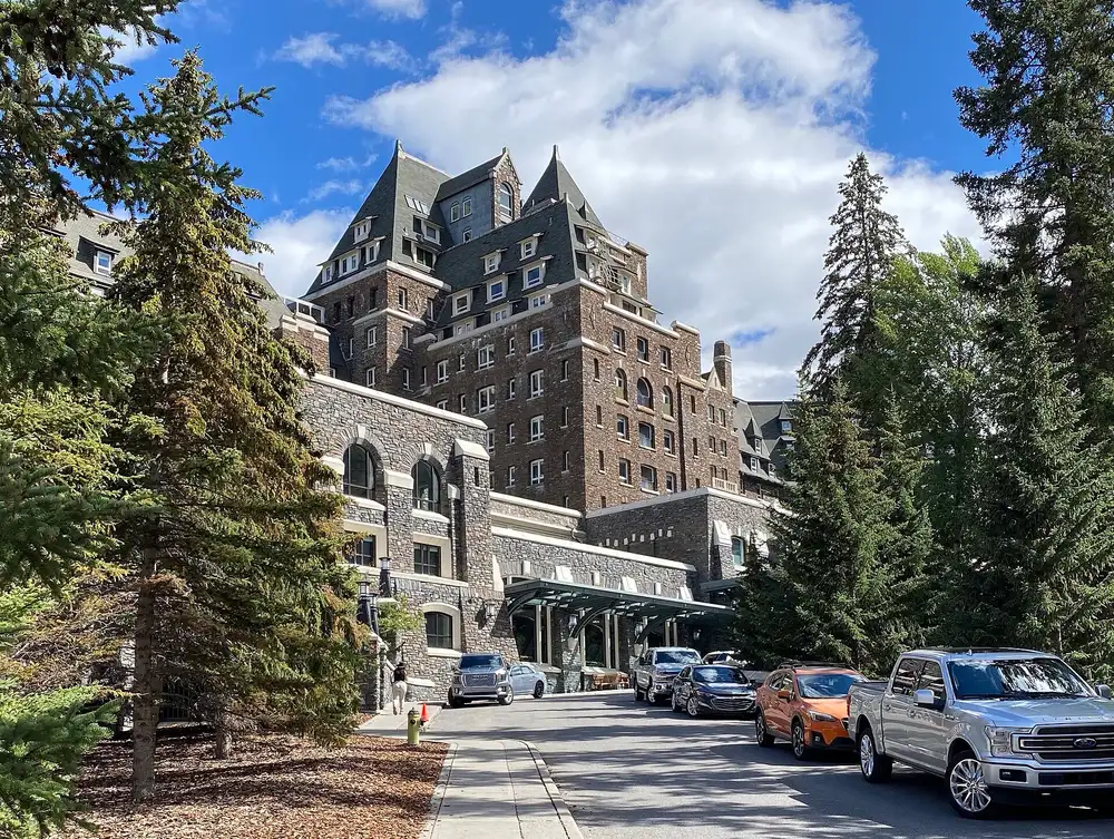 The stone porte-cochere entrance of the Fairmont Banff Springs hotel with arched windows and a flagpole
