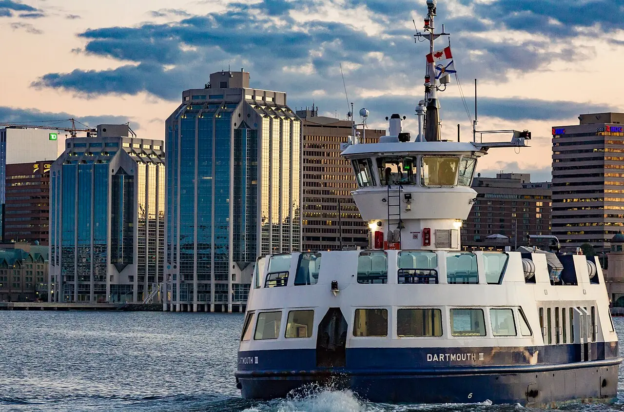 A Halifax Transit ferry crossing the harbour at sunset with the downtown Halifax skyline behind
