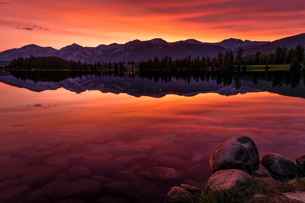 Sunrise over Lac Beauvert in Jasper National Park with mountains reflected in the still water