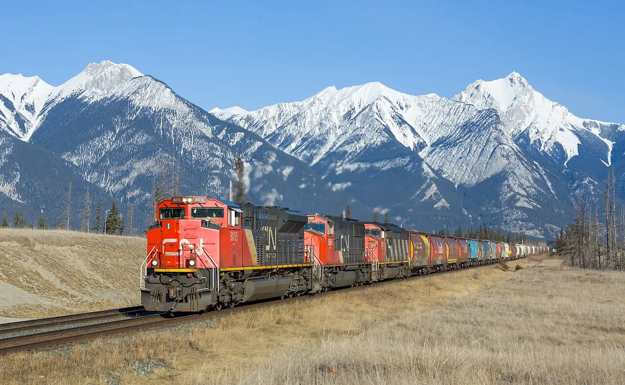 A freight train running along the rail corridor between Hinton and Jasper with snow-capped mountains behind