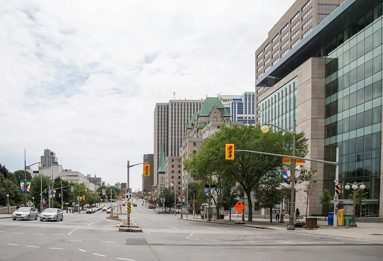 Elgin Street in Ottawa with shops, trees and traffic under a summer sky