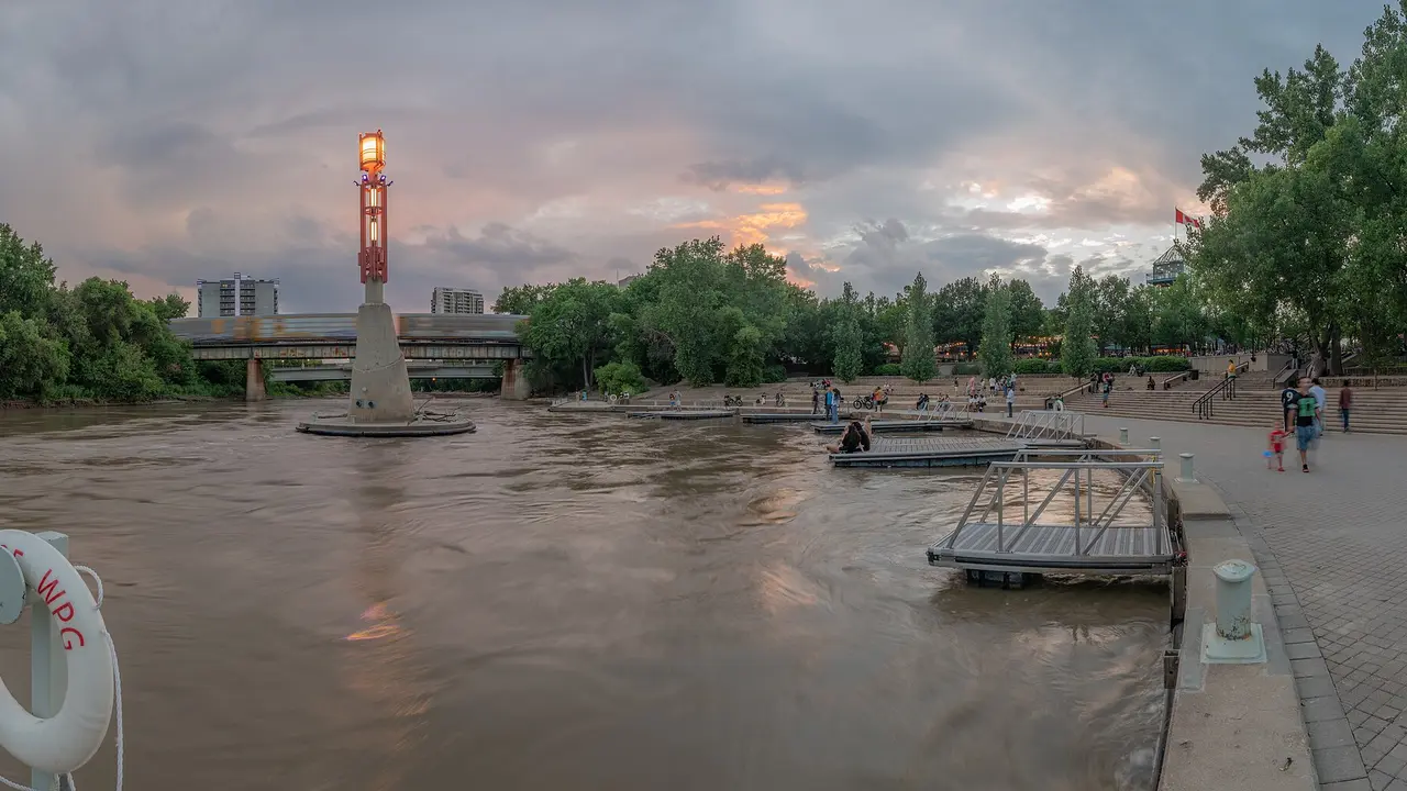 The Forks riverside docks and Provencher bridge in Winnipeg at dusk with the city skyline behind