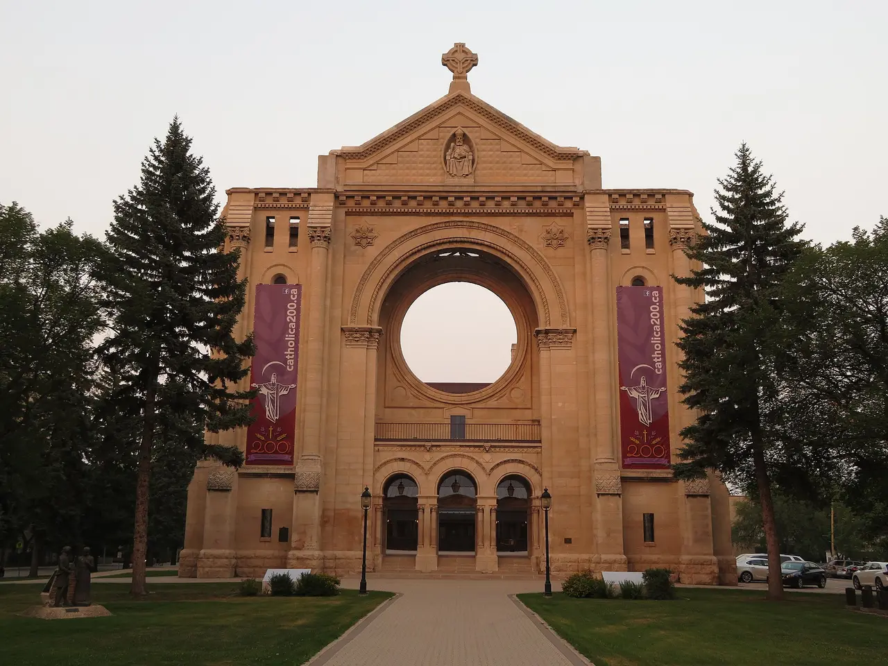 The surviving stone facade and rose window of Saint-Boniface Cathedral in Winnipeg with the modern church behind